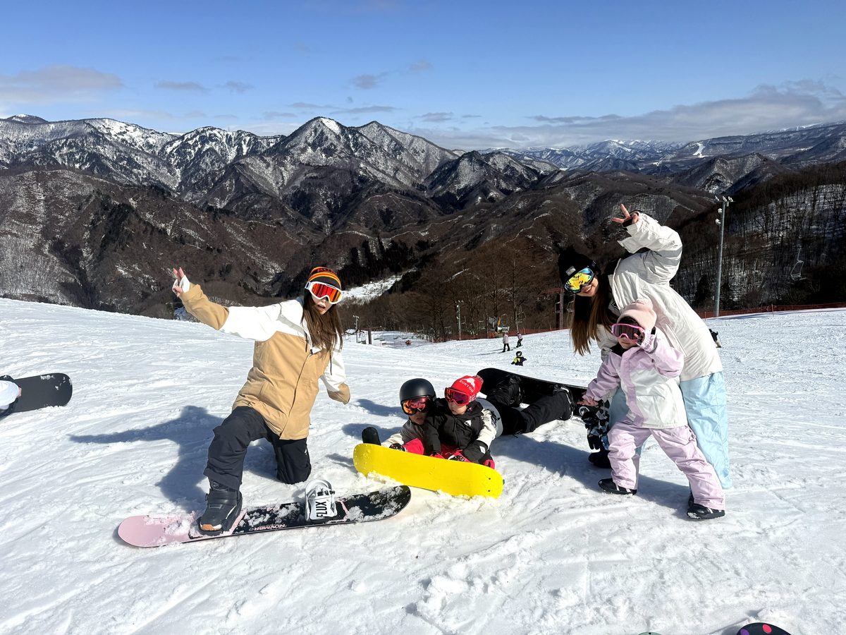 雪山でスノーボードを楽しむ家族グループ