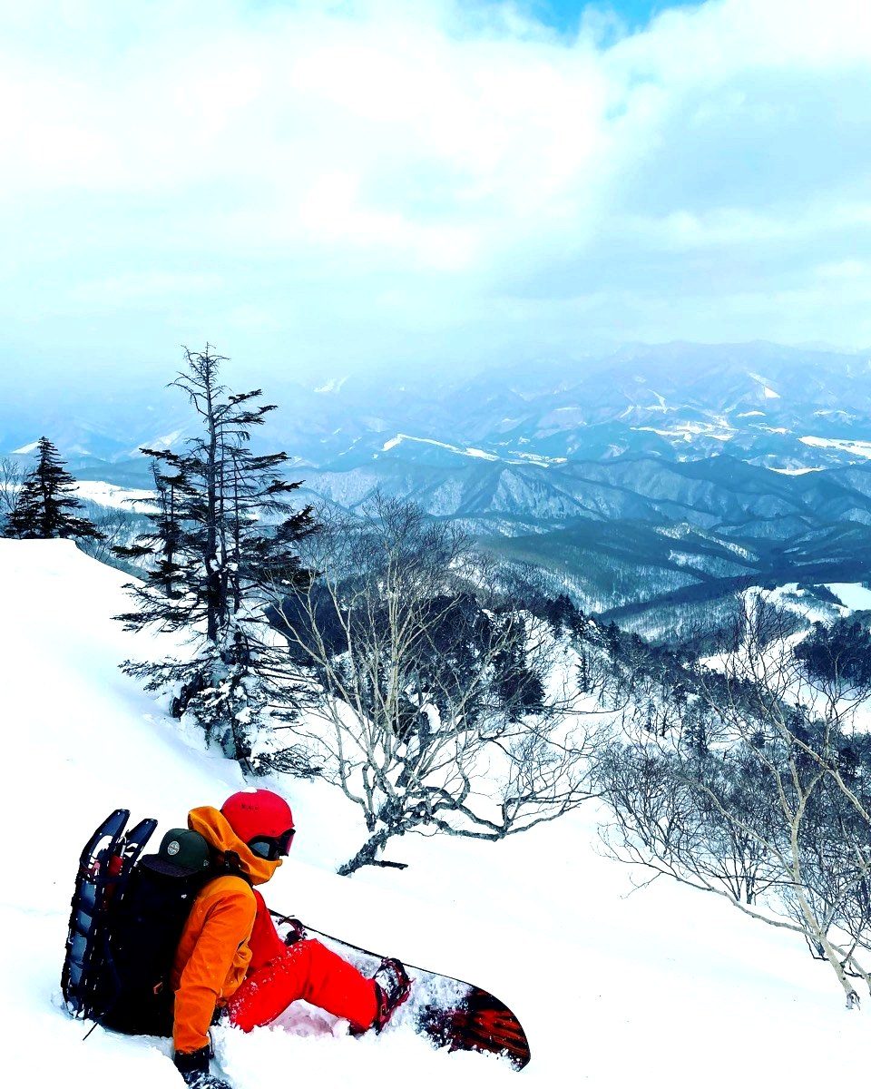 雪山で景色を見ながら休憩する参加者